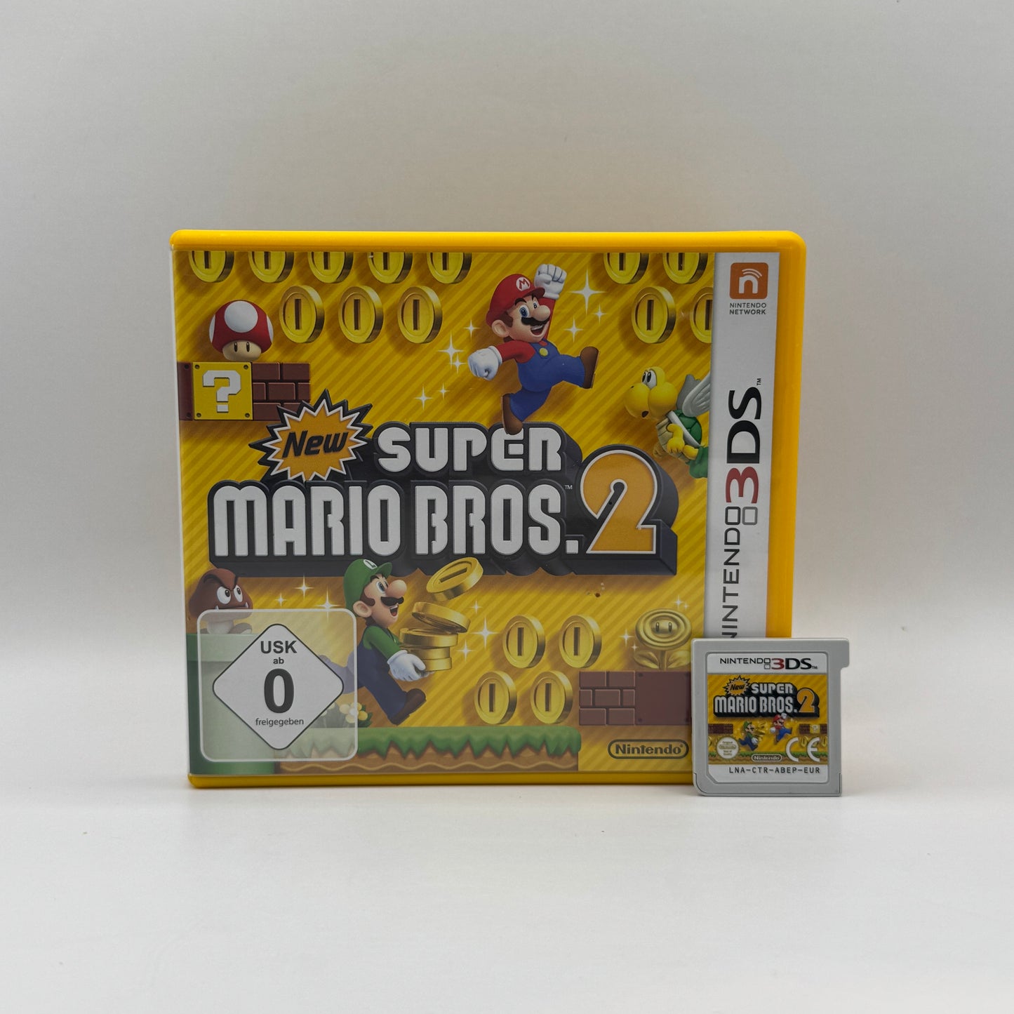 Verpackung des Nintendo 3DS-Spiels New Super Mario Bros. 2, ein Jump’n’Run-Spiel, in dem Mario durch bunte Level läuft, Münzen sammelt und Gegner besiegt.