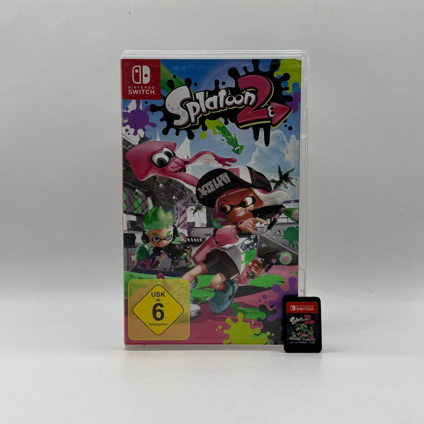 Verpackung des Nintendo Switch-Spiels Splatoon 2, ein farbenfroher Third-Person-Shooter, in dem Spieler als Inklinge in actionreichen Farbkämpfen gegeneinander antreten und ihr Team zum Sieg führen.