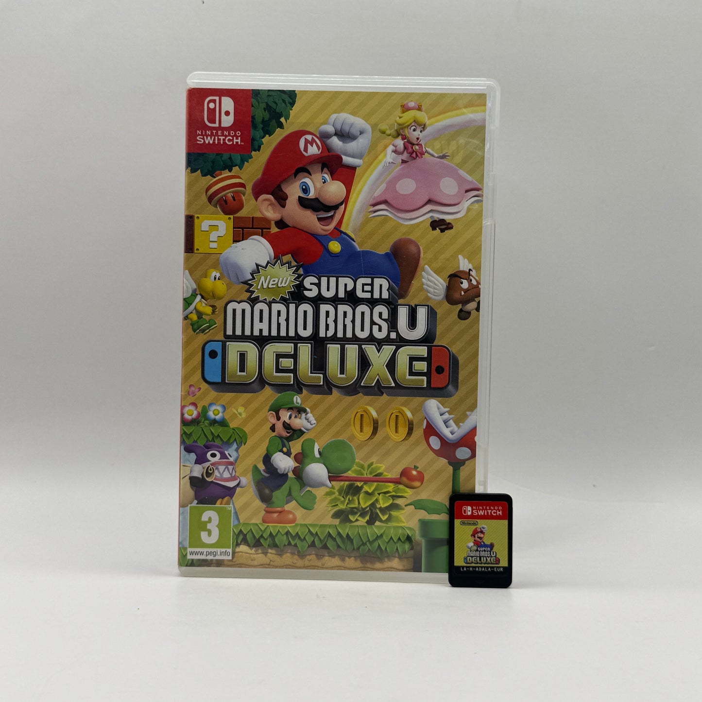 Verpackung des Nintendo Switch-Spiels New Super Mario Bros. U Deluxe, ein Jump’n’Run, in dem Mario, Luigi und weitere Charaktere gemeinsam abwechslungsreiche Level voller Gegner, Geheimnisse und Power-ups meistern.