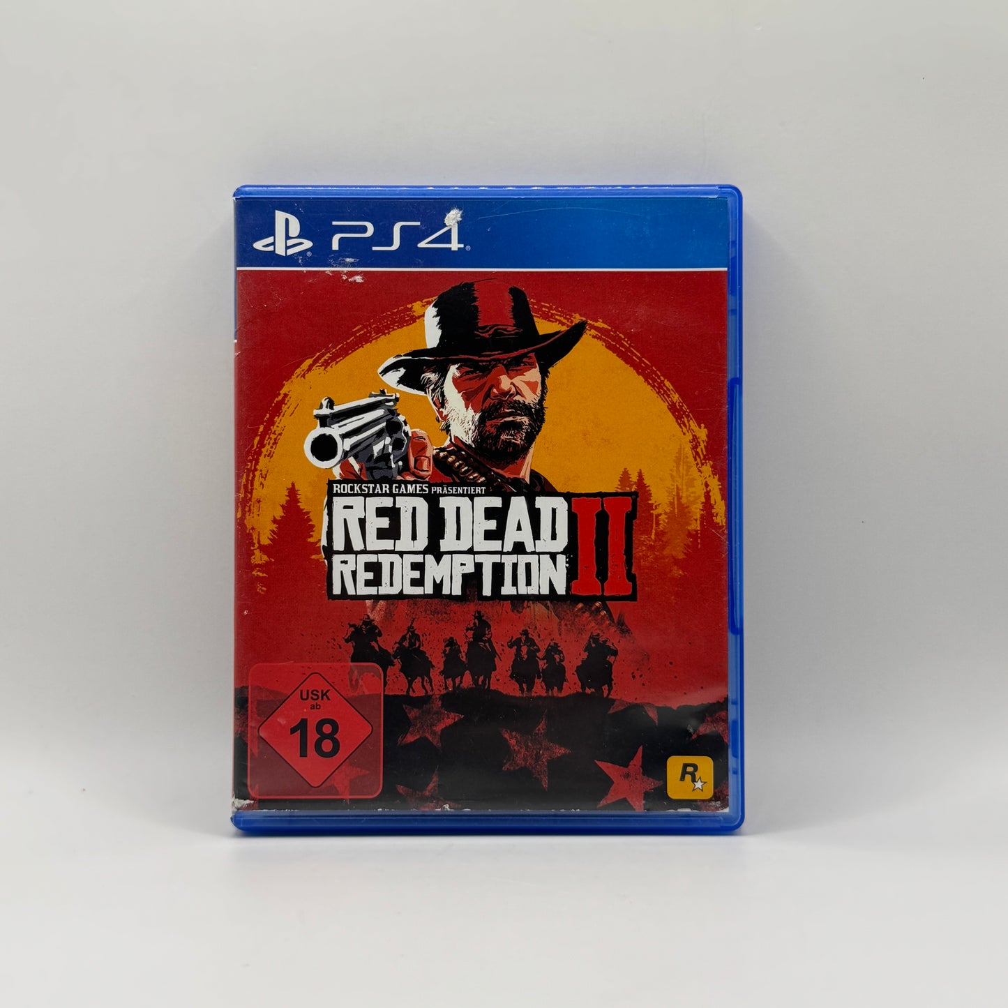 Verpackung des PS4-Spiels Red Dead Redemption 2, ein Open-World-Action-Adventure, in dem Spieler als Arthur Morgan die Wildwest-Welt erkunden, Missionen erfüllen und sich mit Gesetzlosen und Rivalen auseinandersetzen.