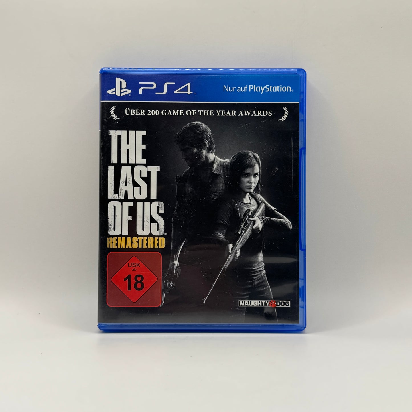 Verpackung des PS4-Spiels The Last of Us Remastered, ein Action-Adventure, in dem Spieler Joel und Ellie durch eine postapokalyptische Welt voller Infizierter und feindlicher Menschen führen, um zu überleben.
