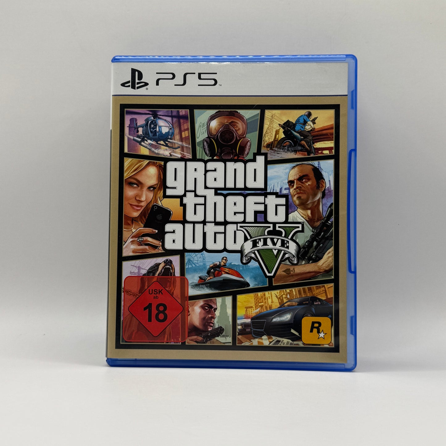 Verpackung des PS5-Spiels Grand Theft Auto V, ein Open-World-Action-Adventure, in dem Spieler drei Charaktere steuern, Missionen erfüllen, die Stadt Los Santos erkunden und in verschiedenen kriminellen Aktivitäten agieren.