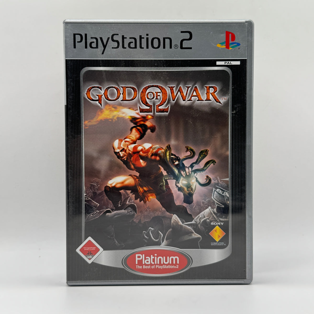 Verpackung des PS2-Spiels God of War, ein Action-Adventure, in dem Spieler als Kratos durch die Welt der griechischen Mythologie kämpfen, mächtige Gegner besiegen und Rätsel lösen.