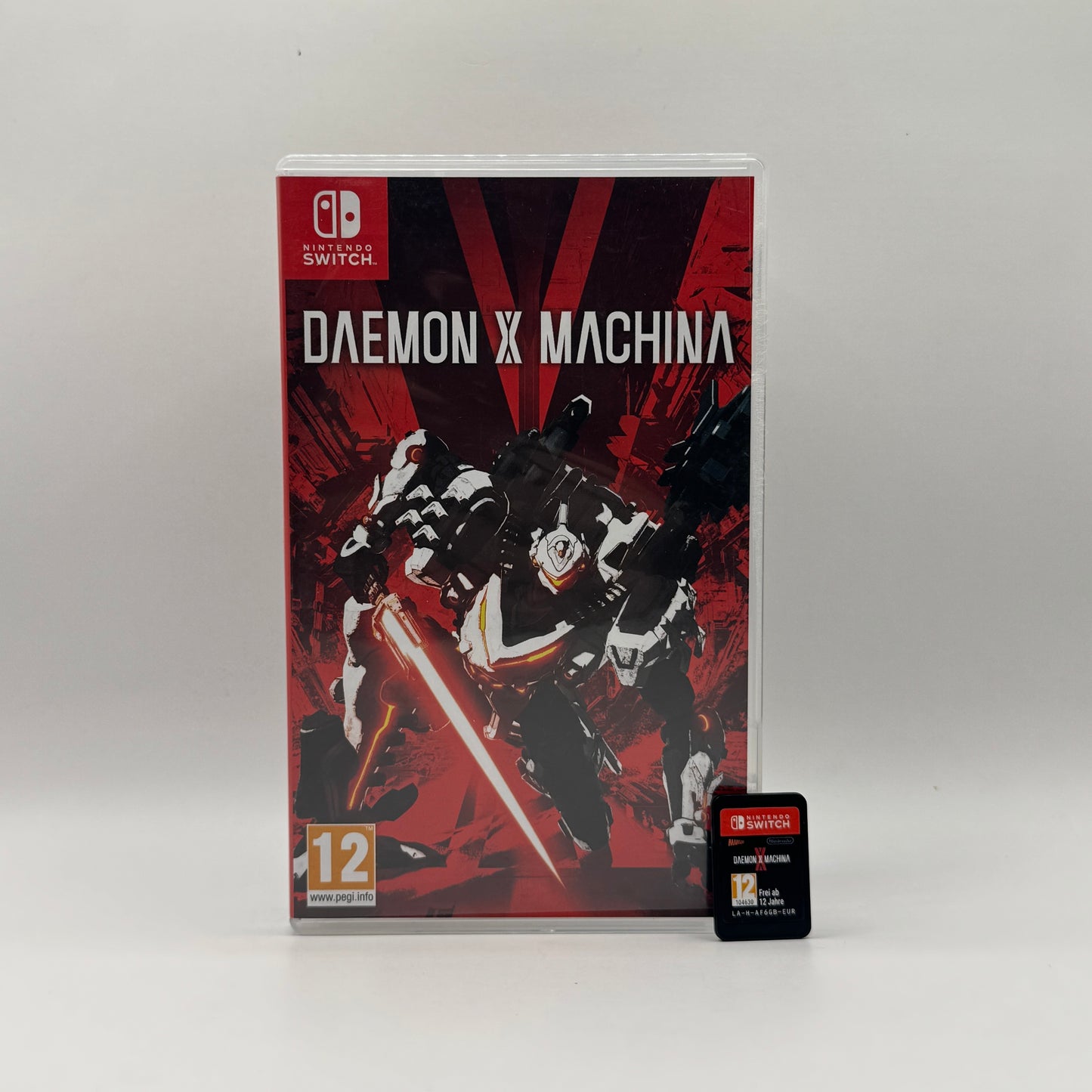 Verpackung des Nintendo Switch-Spiels Daemon X Machina, ein Actionspiel, in dem Spieler in anpassbaren Mechs gegen feindliche Maschinen kämpfen und schnelle Gefechte in futuristischen Umgebungen erleben.