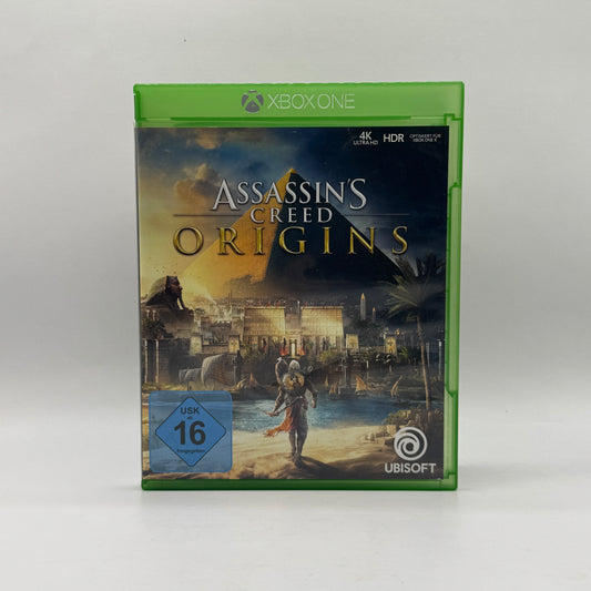 Verpackung des Xbox-One-Spiels Assassin’s Creed Origins, ein Action-Rollenspiel, in dem Spieler als Bayek das antike Ägypten erkunden, Quests erfüllen und Kämpfe bestreiten.